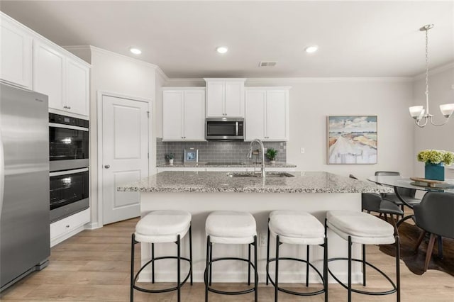 kitchen featuring stainless steel appliances, crown molding, light wood-style flooring, and a sink
