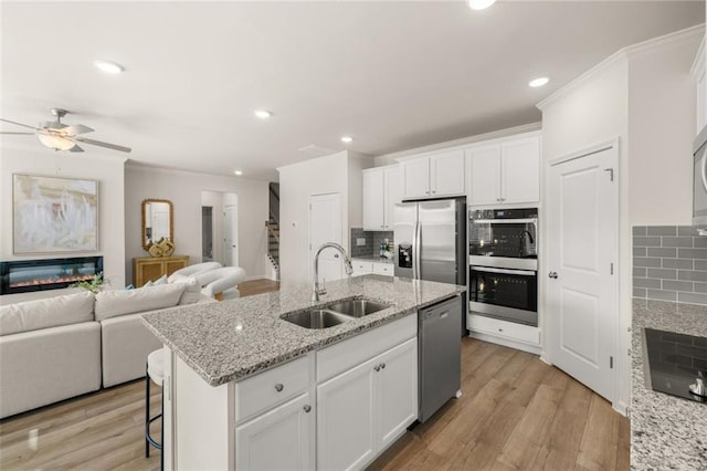 kitchen with backsplash, open floor plan, appliances with stainless steel finishes, and a sink
