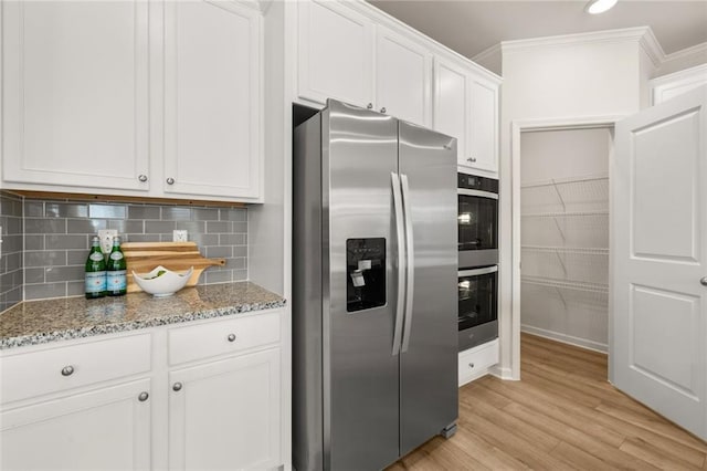 kitchen featuring light stone countertops, light wood-style floors, crown molding, white cabinets, and appliances with stainless steel finishes