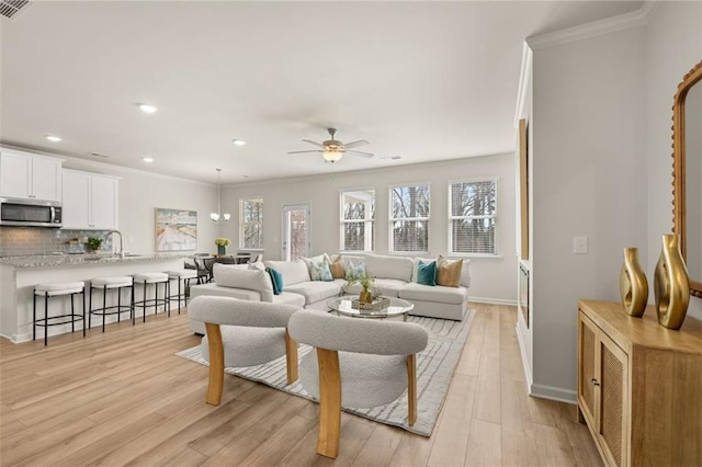 living area with recessed lighting, ceiling fan, baseboards, light wood-type flooring, and crown molding