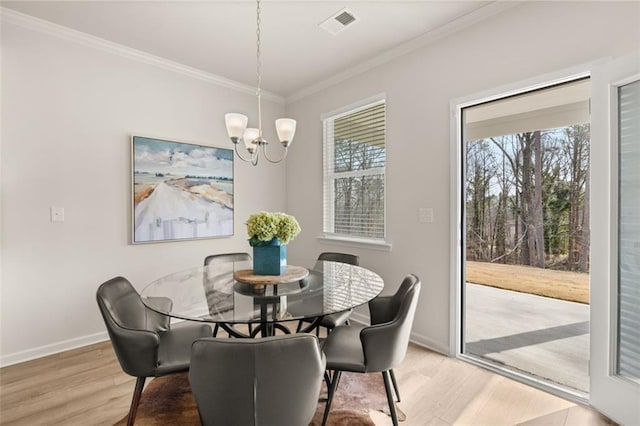 dining space with a chandelier, a wealth of natural light, crown molding, and light wood-style flooring