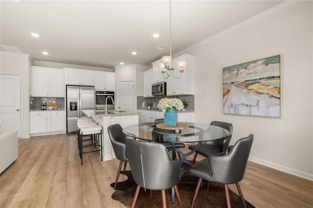 dining room featuring baseboards, light wood-type flooring, ornamental molding, and recessed lighting