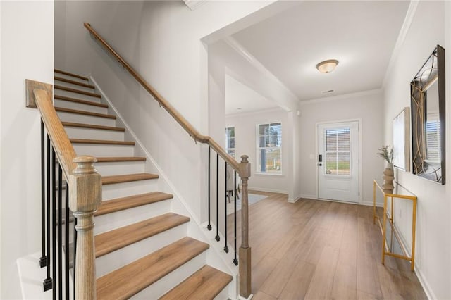 foyer entrance featuring ornamental molding, stairway, wood finished floors, and baseboards