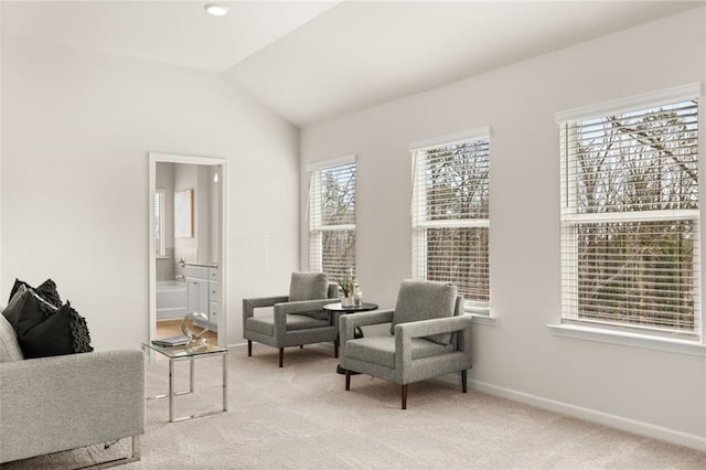 living area featuring light colored carpet, vaulted ceiling, and baseboards