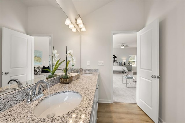 ensuite bathroom featuring wood finished floors, ensuite bathroom, vaulted ceiling, and a sink