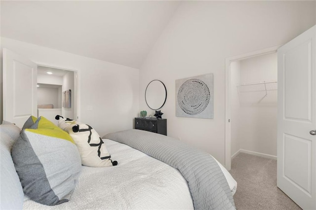 carpeted bedroom with a closet, baseboards, lofted ceiling, and a spacious closet