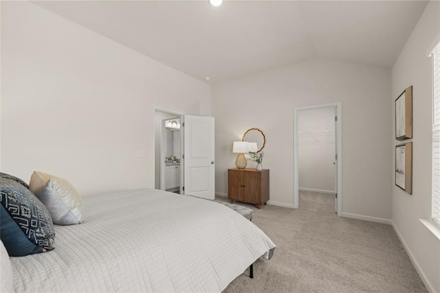 carpeted bedroom featuring a spacious closet, a closet, vaulted ceiling, and baseboards