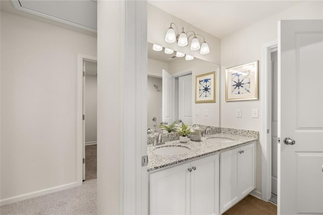 full bath with baseboards, double vanity, and a sink