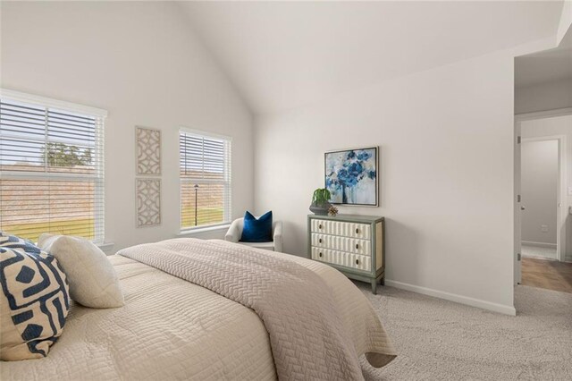 bedroom with baseboards, high vaulted ceiling, and carpet