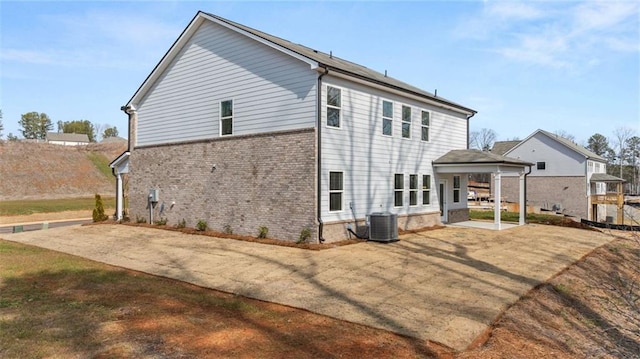 back of property featuring brick siding, cooling unit, and a patio area