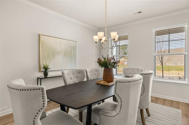dining space with an inviting chandelier, light wood-style floors, baseboards, visible vents, and crown molding