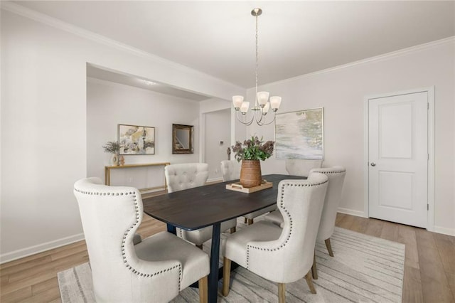 dining room with a chandelier, ornamental molding, and light wood finished floors