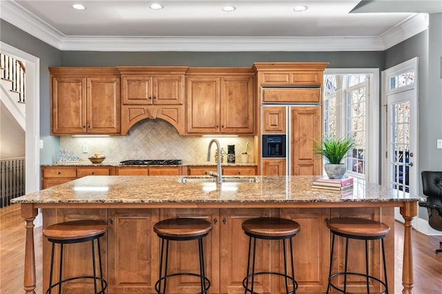 kitchen with a kitchen island with sink, crown molding, and sink