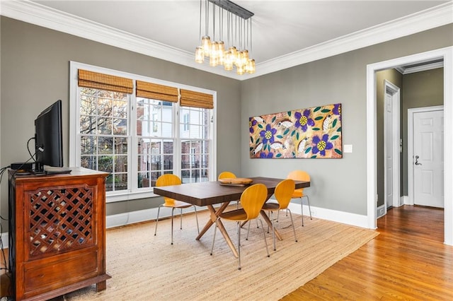 dining room with ornamental molding, light hardwood / wood-style flooring, and an inviting chandelier