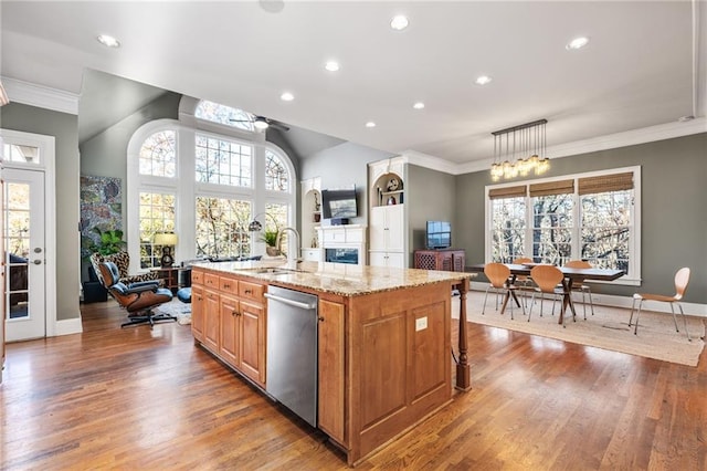 kitchen featuring light stone countertops, sink, a center island with sink, dishwasher, and hanging light fixtures