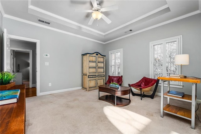 living area with a tray ceiling, ceiling fan, and light colored carpet