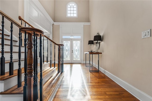 foyer featuring hardwood / wood-style flooring, a high ceiling, and french doors