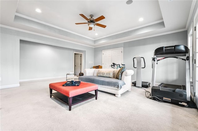 living room featuring carpet floors, a tray ceiling, ceiling fan, and crown molding