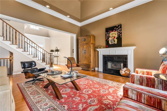 living room featuring crown molding, a high ceiling, and light hardwood / wood-style flooring