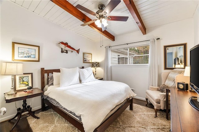 bedroom with beamed ceiling, baseboards, and wood finished floors