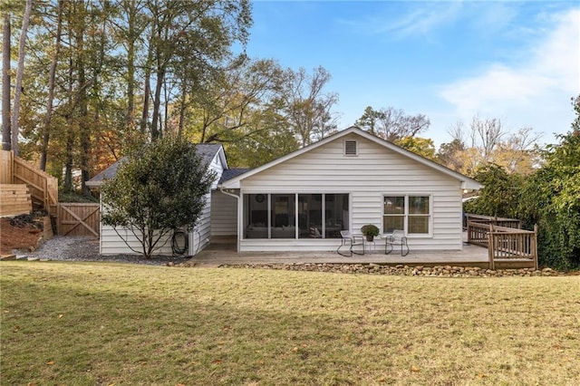 rear view of property featuring a yard, a sunroom, a wooden deck, and fence