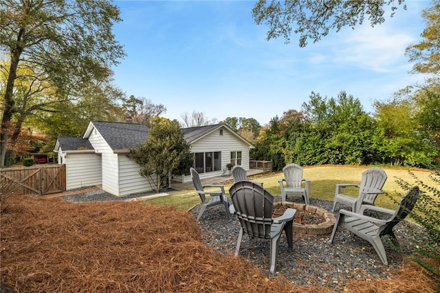 back of property with a lawn, fence, an outdoor fire pit, a shingled roof, and a patio area