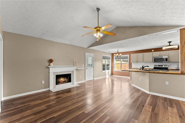 unfurnished living room with vaulted ceiling, dark hardwood / wood-style floors, ceiling fan with notable chandelier, and a textured ceiling