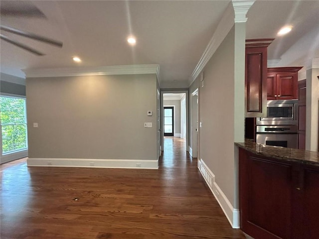 hall with dark wood-type flooring, ornamental molding, and decorative columns