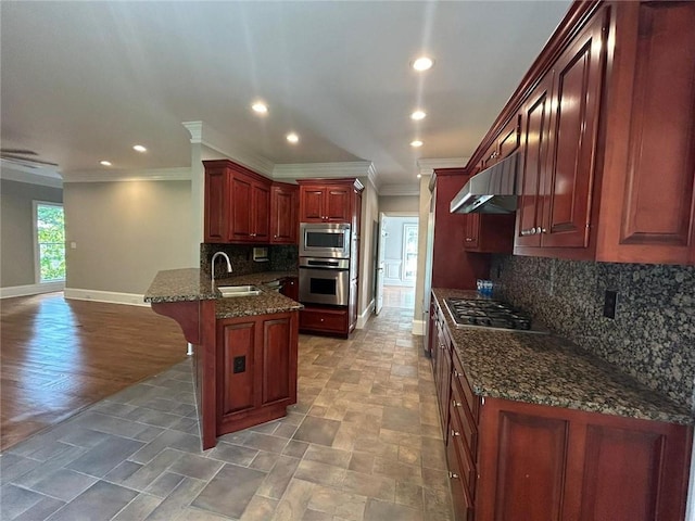 kitchen featuring sink, dark stone countertops, appliances with stainless steel finishes, a kitchen breakfast bar, and kitchen peninsula