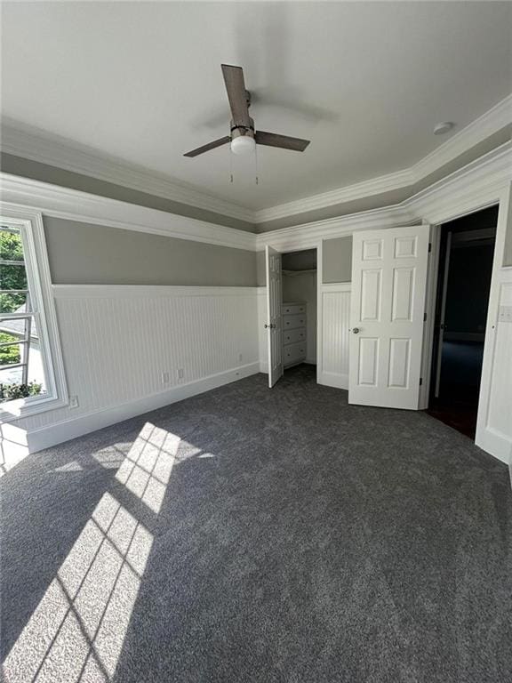 unfurnished bedroom featuring crown molding, ceiling fan, and dark carpet