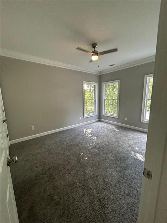 spare room with ceiling fan, ornamental molding, and dark carpet