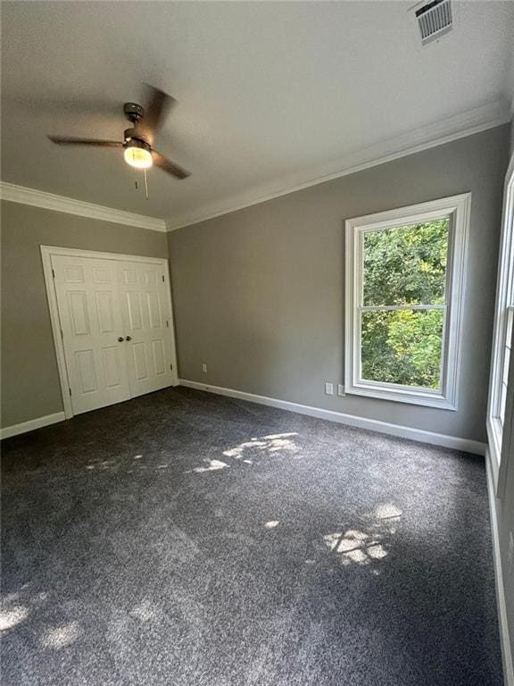 unfurnished bedroom with ceiling fan, ornamental molding, a closet, and dark colored carpet