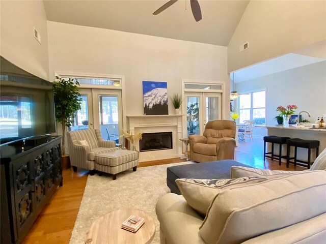 living room with a high ceiling, hardwood / wood-style flooring, and ceiling fan with notable chandelier