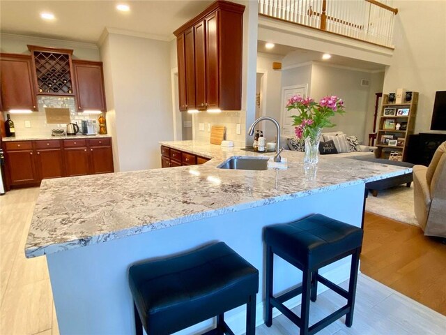 kitchen featuring sink, a breakfast bar area, crown molding, appliances with stainless steel finishes, and light stone countertops