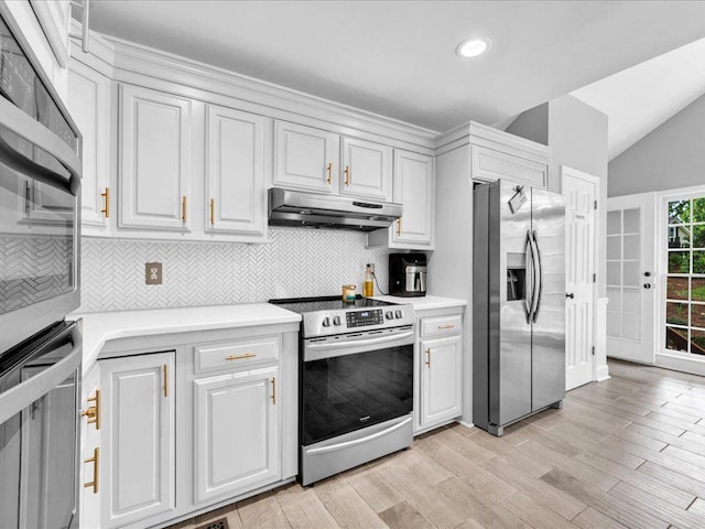 kitchen with appliances with stainless steel finishes, under cabinet range hood, backsplash, light countertops, and vaulted ceiling