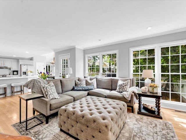 living room with ornamental molding, light wood-type flooring, a chandelier, and recessed lighting