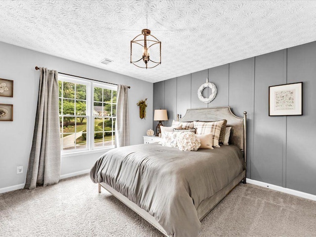 carpeted bedroom featuring a chandelier, baseboards, and a textured ceiling