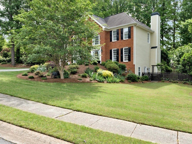 colonial-style house with a chimney, brick siding, and view of scattered trees