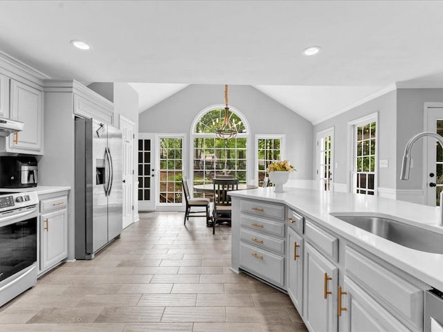 kitchen with stainless steel appliances, a sink, lofted ceiling, light countertops, and recessed lighting