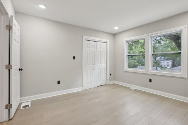 unfurnished bedroom with a closet and light wood-type flooring