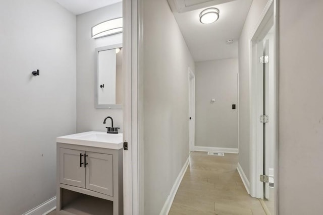 corridor with sink and light wood-type flooring