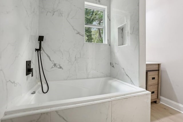 bathroom featuring wood-type flooring and tiled bath