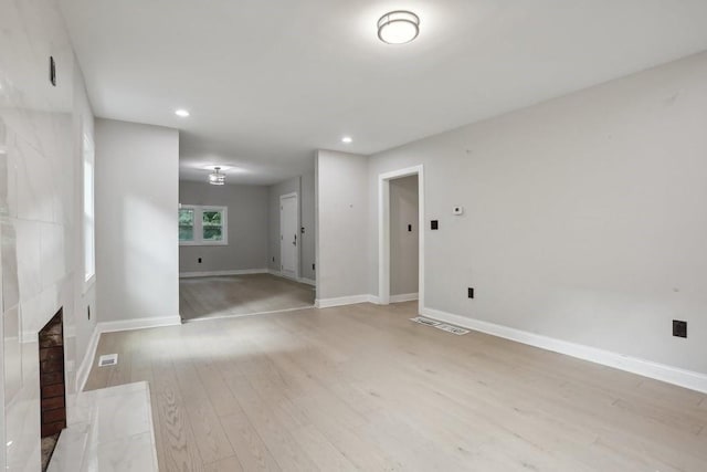 unfurnished living room featuring a tiled fireplace and light hardwood / wood-style flooring