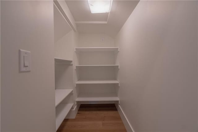 spacious closet with light wood-type flooring and vaulted ceiling