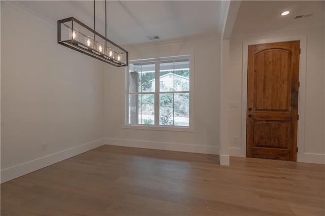 unfurnished dining area featuring crown molding and light wood-type flooring