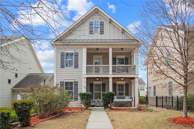 view of front facade featuring a front yard, a balcony, fence, and board and batten siding