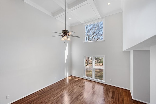 unfurnished living room with a healthy amount of sunlight, coffered ceiling, wood finished floors, and beamed ceiling