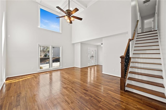 unfurnished living room featuring ceiling fan, stairway, baseboards, and wood finished floors