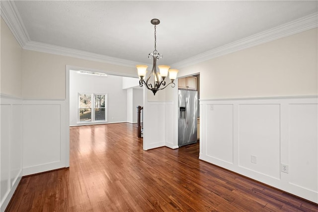 unfurnished dining area with crown molding, dark hardwood / wood-style floors, and a chandelier