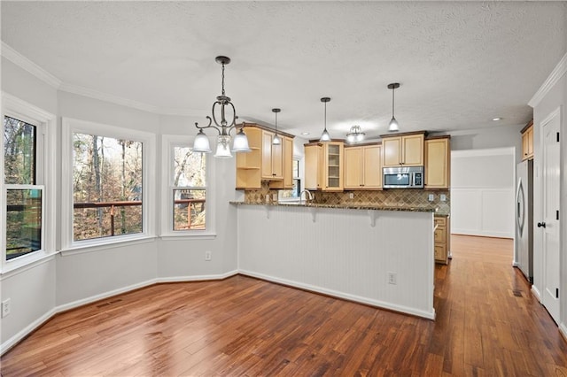 kitchen with decorative backsplash, appliances with stainless steel finishes, glass insert cabinets, a breakfast bar, and a peninsula